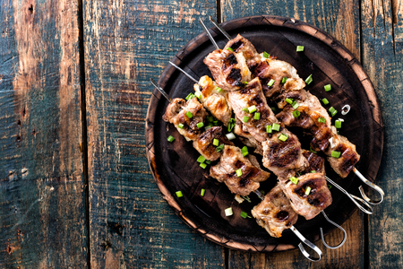 Grilled meat skewers, shish kebab on wooden background, top viewの写真素材