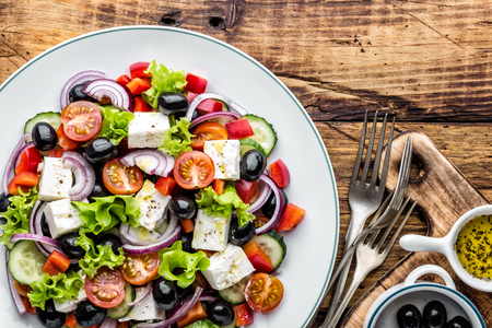 Greek salad of fresh cucumber, tomato, sweet pepper, lettuce, red onion, feta cheese and olives with olive oil. Healthy vegetarian foodの写真素材