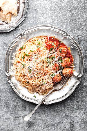 spaghetti bolognese with meatballs in tomato sauce sprinkled with parmesan cheeseの写真素材