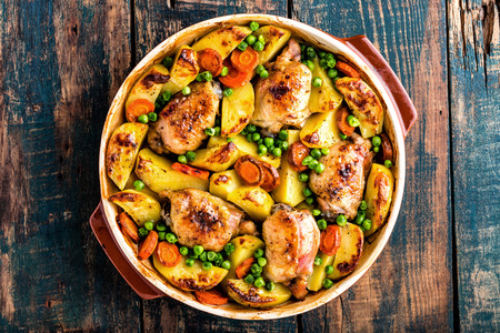 Chicken thighs baked with potato, carrot and green peasの写真素材