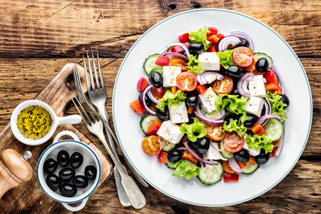 Greek salad of fresh cucumber, tomato, sweet pepper, lettuce, red onion, feta cheese and olives with olive oil. Healthy vegetarian foodの写真素材