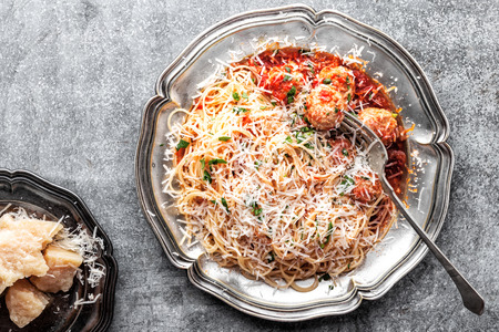 spaghetti bolognese with meatballs in tomato sauce sprinkled with parmesan cheeseの写真素材