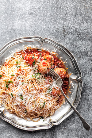 spaghetti bolognese with meatballs in tomato sauce sprinkled with parmesan cheeseの写真素材