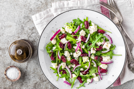 A plate of nutritious simple salad with arugula, beans, soft cheese, onions and oilの写真素材