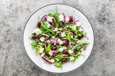 A plate of nutritious simple salad with arugula, beans, soft cheese, onions and oilの写真素材