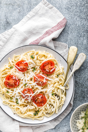 cooked noodles on a table in a plate with tomatoes, parmesan cheese and spicesの写真素材