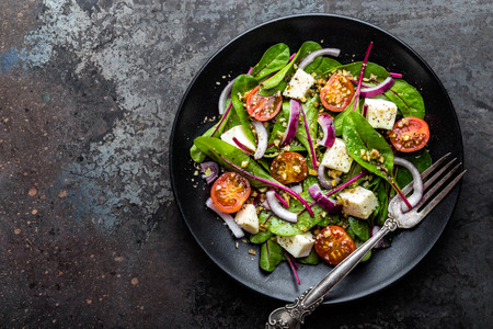 plate of nutritious simple salad with chard, walnuts, soft cheese, onions and oil, top view, space for textの写真素材