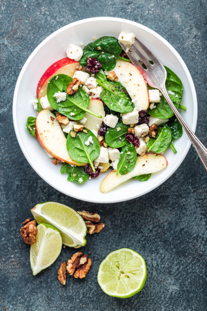 salad bowl of spinach, apple, soft cheese, nuts and cranberry. top view, healthy diet eating, superfoodの写真素材