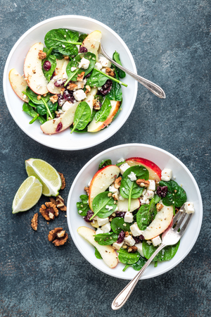 salad bowl of spinach, apple, soft cheese, nuts and cranberry. top view, healthy diet eating, superfoodの写真素材