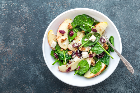 salad bowl of spinach, apple, soft cheese, nuts and cranberry. top view, healthy diet eating, superfoodの写真素材