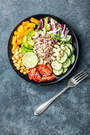 Vegetarian salad Buddha bowl dish with brown rice, avocado, pepper, tomato, cucumber, chickpea, chia seeds, fresh lettuce salad and cashew nuts. Healthy eating trend, superfood. Top viewの写真素材