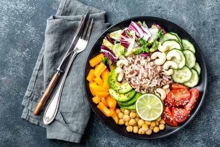 Vegetarian salad Buddha bowl dish with brown rice, avocado, pepper, tomato, cucumber, chickpea, chia seeds, fresh lettuce salad and cashew nuts. Healthy eating trend, superfood. Top viewの写真素材