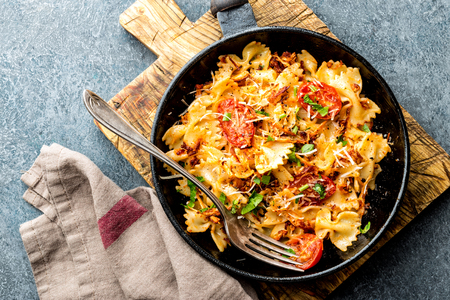 pasta farfalle with roasted meat and tomatoes in a frying panの写真素材