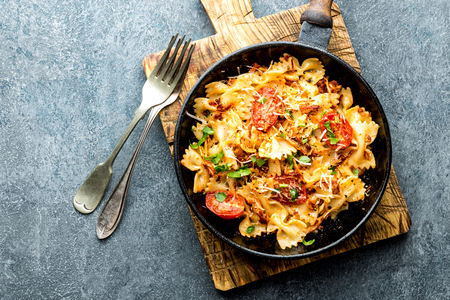 pasta farfalle with roasted meat and tomatoes in a frying panの写真素材