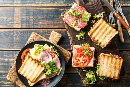 sandwiches with grilled toast ham salami cheese tomatoes and lettuceの写真素材