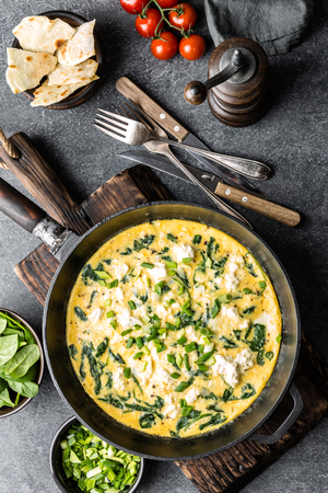 omelette with spinach and cheese in a pan on the concrete background top viewの写真素材