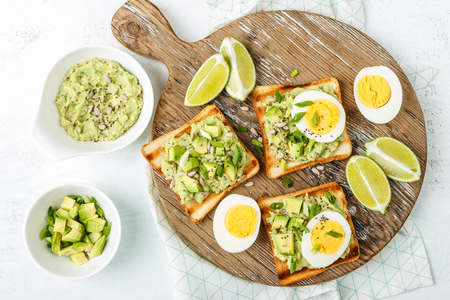 avocado toasts, healthy snack of grilled bread with guacamole slices avocado, boiled eggs, chia seeds and green onionsの写真素材