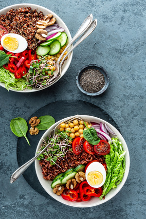 Healthy salad Buddha bowl dish of brown rice, pepper, tomato, cucumber, chickpea, chia, sprouts, savoy and nuts. Healthy eating trend, superfood. Top viewの写真素材
