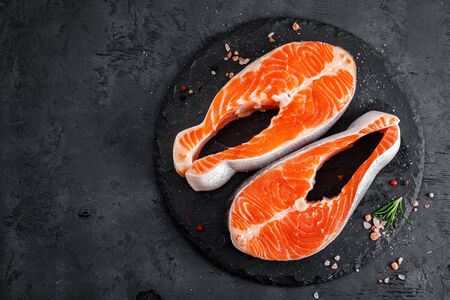 Raw salmon fish steaks on black backgroundの写真素材