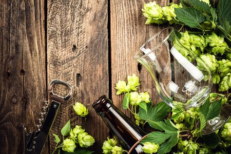 beer background of empty beer glass, bottle and fresh hops on an old wooden table. top view. space for a textの写真素材