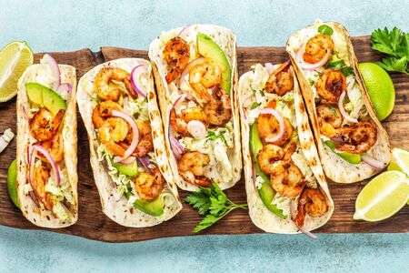 Shrimp tacos. Seafood fajitas with cabbage, onion, parsley in tortillas served on wooden cutting boardの写真素材