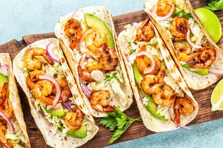 Shrimp tacos. Seafood fajitas with cabbage, onion, parsley in tortillas served on wooden cutting boardの写真素材