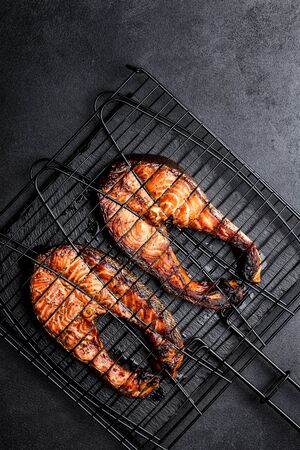 Grilled salmon on iron grill grate on a dark background top view. BBQ seafood. space for a textの写真素材