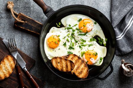 fried eggs in a cast iron pan top viewの写真素材