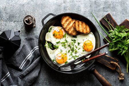 fried eggs in a cast iron pan top viewの写真素材