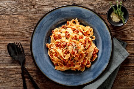 Pasta bolognese. Traditional italian dish of pasta with tomato and meat mince sauce served in a plate with parmesan cheese and thyme, top viewの写真素材