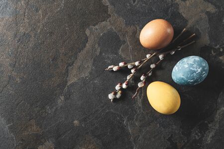 Easter background with space for a text. Natural dyed easter eggs on dark stone background.の写真素材