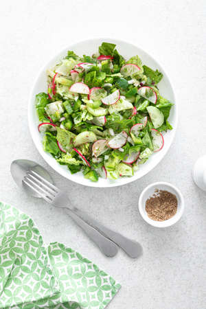 Salad bowl of fresh vegetables with radish, cucumber, romaine lettuce, bell pepper and greens. Healthy foodの写真素材