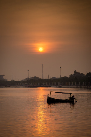 Fishing boat silhouette against sunrise sky at Ancolの写真素材