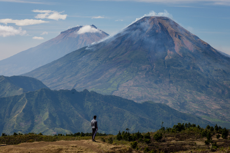 A man stands looking at the beauty of Sindoro and Sumbing mountainsの写真素材