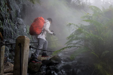 A man is crossing the path of a hot spring stream in the Gunung Gede Pangrango forestの写真素材