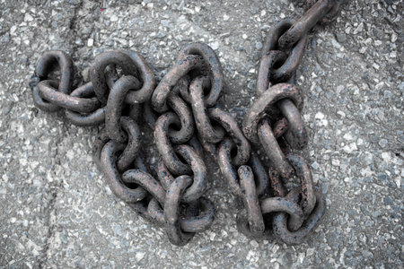 A large, long chain against the backdrop of the sidewalk. Close-up