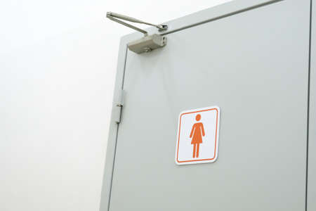 Toilet sign on the toilet door. Women WC signs for toilet. Women's bathroom on a white wallの写真素材