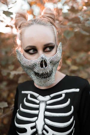 Girl dressed as a skeleton in the autumn forest. Portrait. Close-up. Halloween