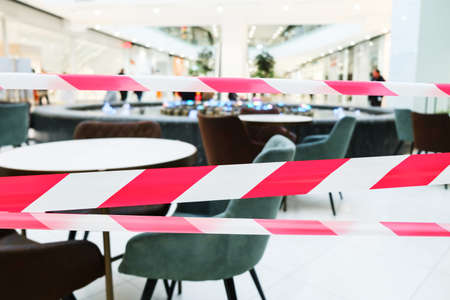 Red and white lines of barrier tape. Indoor food court in a shopping center. Red White Warning Tape...