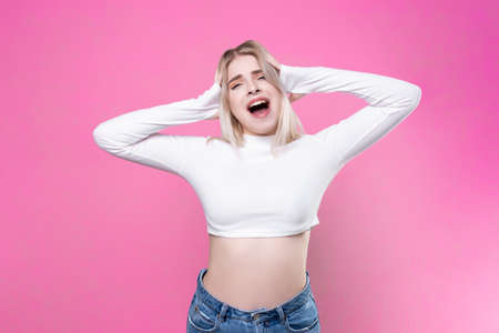 Beautiful attractive young blonde. Studio portrait, close-up. Shouts and covers his ears with his...