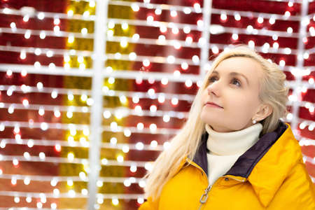 Beautiful, young fairy-tale blonde girl posing in the light of New Year's lights. Look away and smile. Orders a desire. New year and christmas conceptの写真素材