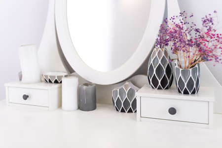 Bathroom accessories. Cosmetic table with a mirror, candles, dried flowers. Home decor