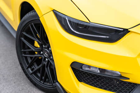 Yellow with black stripes Ford Mustang muscle car in a parking lot. Close-up of headlight and wheel. Russia, Rostov-on-Don 23 Oct2021のeditorial素材