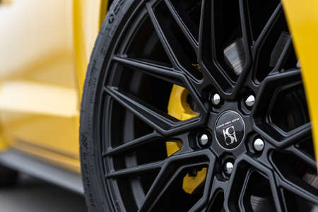 Yellow with black stripes Ford Mustang muscle car in a parking lot. Wheel close-up. Russia,...
