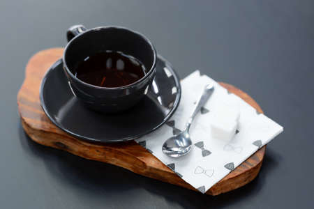 Black coffee cup and spoon on a wooden standの写真素材