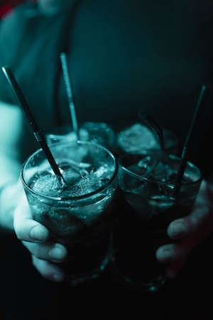 Cocktails in the hands of the bartender in blue light