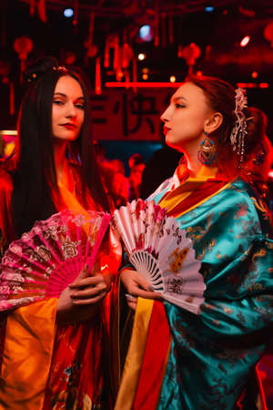 Two beautiful girls in kimono with fans in their hands. The image of a geisha, Chinese national costume. Party concept, night club. Russia, Rostov-on-Don 5feb2022のeditorial素材