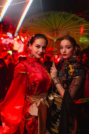 Two beautiful girls in a kimono with an umbrella in their hand. Image of a geisha, Chinese national costume. Party concept, night club. Russia, Rostov-on-Don 6feb2022のeditorial素材