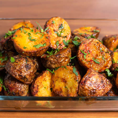 Fried potato wedges with thyme, close-up on a plate on a wooden tableの写真素材