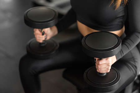 Sports woman performs exercises with dumbbells. Photo of a muscular woman in sportswear. strength...